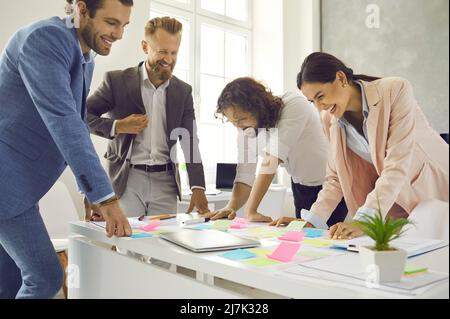 Smiling gen Z coworkers brainstorm discuss ideas in office Stock Photo