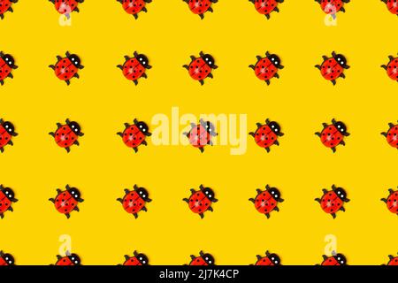 Seamless pattern made with ladybugs on yellow background, as backdrop or texture. Bright summer wallpaper. Top view Flat lay. Stock Photo