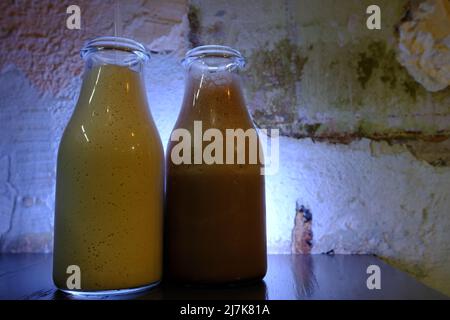 Milkshake chocolate milk in bottles with straws vintage blue neon lighted background closu up side view. Stock Photo