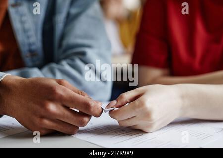 Closeup of two students passing note in secret gossiping or cheating on test, copy space Stock Photo