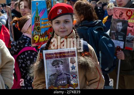 Moscow, Russia. 9th May, 2022. A girl in a uniform of the All-Russia 'Yunarmia' (Young army) National Military Patriotic Movement holds a portrait of her relatives (WWII soldier) during the Immortal Regiment march at Tverskaya street in Moscow, Russia. The event celebrates the Soviet Union's defeat of Nazi Germany in World War II Stock Photo