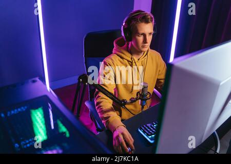 Happy professional player streaming esport tournament using microphone and  headphones, enjoying a multiplayer game. Competitive gamer playing online  video game at home. Neon color. Cyber sport concept Stock Photo