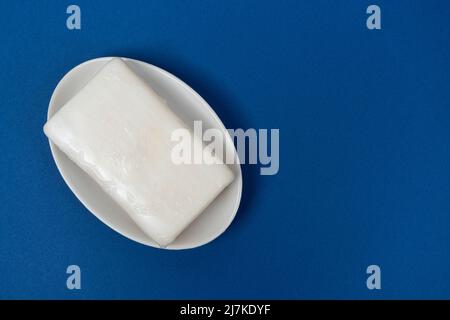 a bar of soap on a soap dish on a blue background Stock Photo