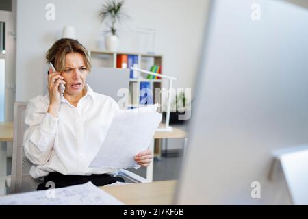 Business woman with a surprised face talking on the phone while looking at documents Stock Photo