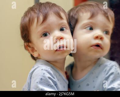 A portrait of a one-year-old boy reflected in a mirror Stock Photo