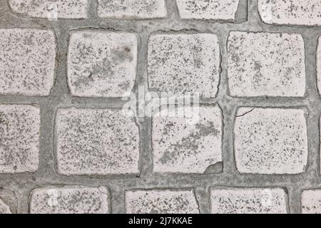 Full frame background of shabby pavement made of uneven square stones and concrete on town street Stock Photo