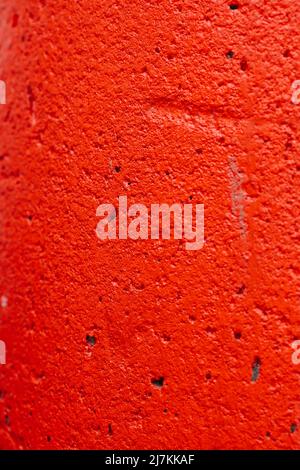 Textured background of rough plaster wall of building painted with bright red color Stock Photo