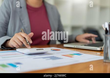 Business analyst concept the accountant using calculator to check the correctness of the data in the laptop. Stock Photo