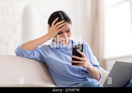 Chinese businesswoman using laptop and smartphone at home Stock Photo