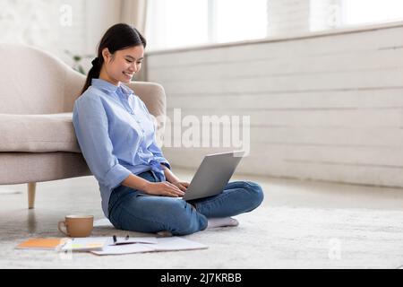 Attractive asian woman sitting on floor with laptop Stock Photo