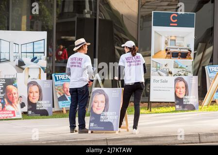 Chatswood, Sydney, Australia May 10th, 2022: Volunteers stand beside sandwich board posters of candidates and wait to hand out how to vote pamphlets to people attending the pre-polling station in Chatswood on Sydney's north shore in New South Wales, Australia. Voting in Australia is compulsory and certain categories of voters qualify to vote within two weeks of the coming election on May 21st Stock Photo