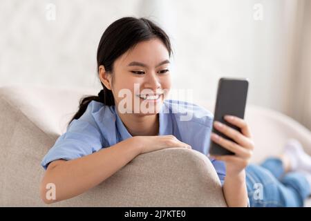 Closeup of cheerful korean woman using smartphone Stock Photo