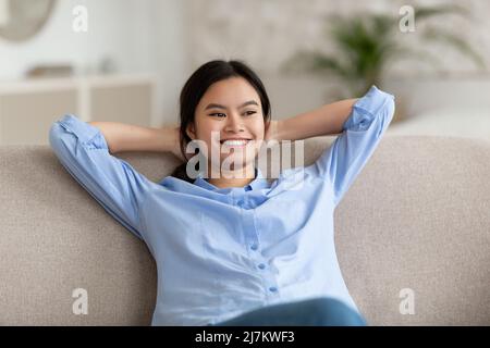 Cute chinese woman resting on sofa at home Stock Photo