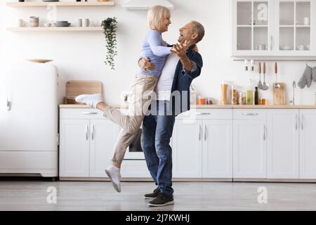 Romantic elderly man and woman dancing at kitchen Stock Photo