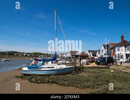 Sailing boats moored on the beach front of the estuary of the River Colne along with the building of the ancient town of Wivenhoe, Essex, England, UK Stock Photo