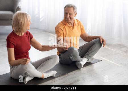 Athletic senior couple meditating together at home Stock Photo