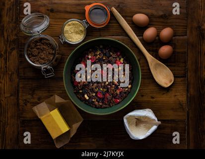 Flat lay on a dark wooden table of ingredients ready to make a fruit cake. Stock Photo