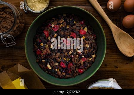Flat lay composition on a dark wooden table of ingredients ready to make a fruit cake. Stock Photo