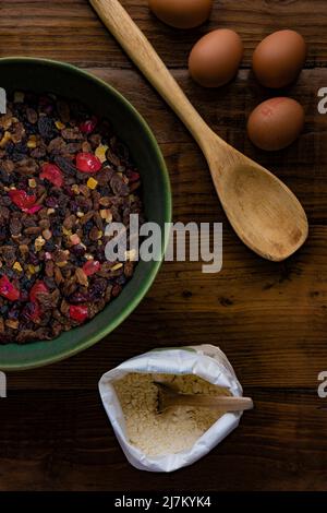 Flat lay composition on a dark wooden table of ingredients ready to make a fruit cake. Stock Photo