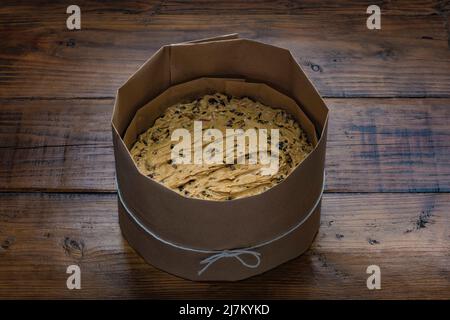 Fruit cake batter in a round tin lined with baking parchment, with brown paper tied with string around the outside ready to be baked. Stock Photo