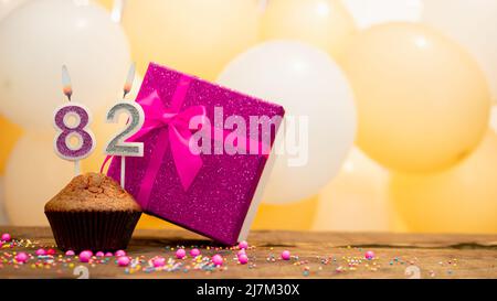 Happy birthday with pink gift box for baby girl. Beautiful birthday card with a cupcake and a burning candle Stock Photo