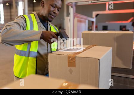 African american young male warehouse worker scanning barcode with reader on cardboard box Stock Photo
