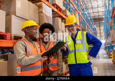 Smiling asian mature man with african american young male and female coworkers looking at clipboard Stock Photo