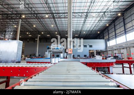 Empty conveyor belt with illuminated lights hanging on ceiling in distribution warehouse Stock Photo