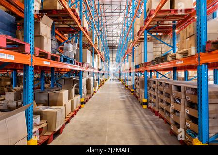 Diminishing perspective of flooring amidst shelves with cardboard boxes in storage compartment Stock Photo
