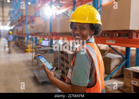 Portrait of smiling confident african american young female warehouse worker using digital tablet Stock Photo