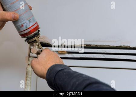 Home reconstruction with worker install wooden door, using polyurethane foam to mounting Stock Photo