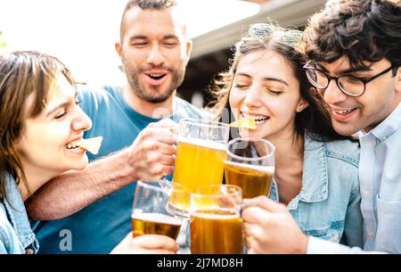 Young friends drinking and toasting beer pints at brewery bar garden out side - Beverage life style concept with men and women having fun together Stock Photo