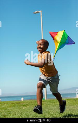 Happy african american boy running with colorful kite against clear blue sky with copy space Stock Photo