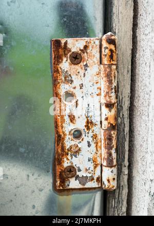 Close-up view of an old rusty hinge on aluminium door. Stock Photo
