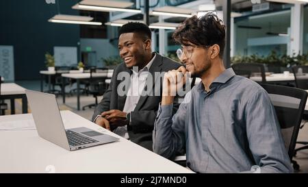 Side view diverse happy colleagues men african businessman talking with arabian employee worker having fun together pleasant conversation multiracial Stock Photo