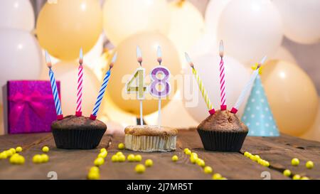 Beautiful birthday card for a girl with a cupcake on the background of balloons. Happy birthday girl, gift box on the background of burning candles. Stock Photo
