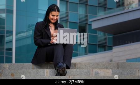 Young businesswoman talking using webcam on laptop outdoors speaking into camera at remote interview female coach distance teacher makes conference Stock Photo