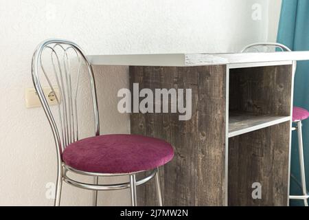 a tall purple bar stool near a minimalist table in a window room Stock Photo