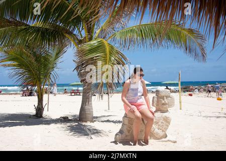 Young woman sitting on Mayan statue, El Pescador Marisqueria & Bar, Playa Chen Rio,  Cozumel, Quintana Roo, Mexico Stock Photo