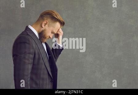 Portrait depressed businessman touching head suffering from headache side view Stock Photo