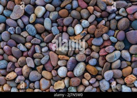 Mineral background featuring river stones in muted colors scattered evenly on the ground, high angle close-up view of small pebbles laid flat Stock Photo