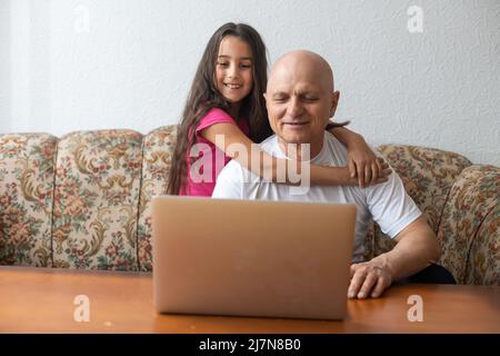 Grandfather and granddaughter spend time together use laptop, browse website, younger generation teach explain to older how to use modern tech concept Stock Photo