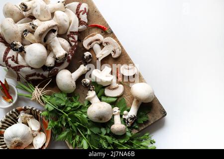 Fresh champignon mushrooms and ingredients for cooking on white background. Cooking organic mushroom. Directly above. Copy space. Stock Photo