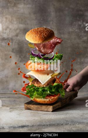 Levitation food concept. Delicious burger with flying ingredients on textured background Stock Photo