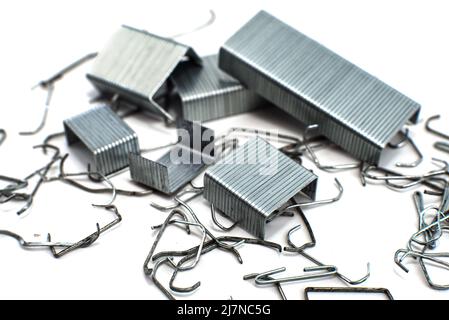 Staples from a stapler on a white background. Isolate of a bunch of staples scattered on the surface Stock Photo
