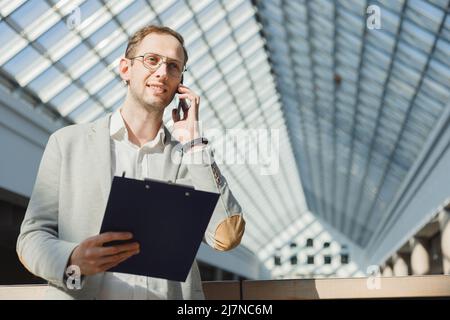 Man in suit with folder makes survey on phone, an anonymous survey, cold calls, business proposal, sales. Stock Photo