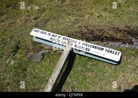 Sign post to hut of shadows in the  Millennium forest follow markers Lockmaddy North Uist Scotland broken sign fallen down on grass follow markers Stock Photo