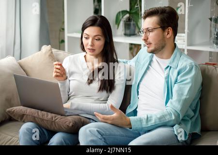 A young couple is working in front of a laptop. Stock Photo
