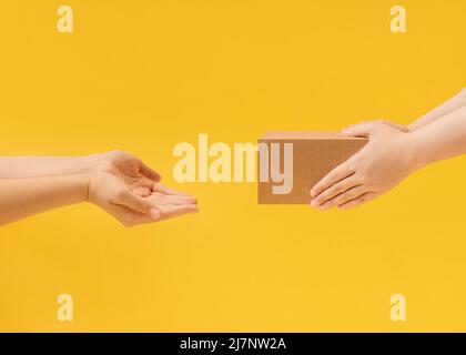 Hands handing over a parcel in a cardboard box Stock Photo