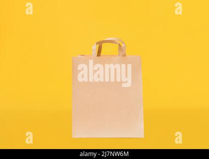 Kraft bag with handles on yellow backdrop Stock Photo